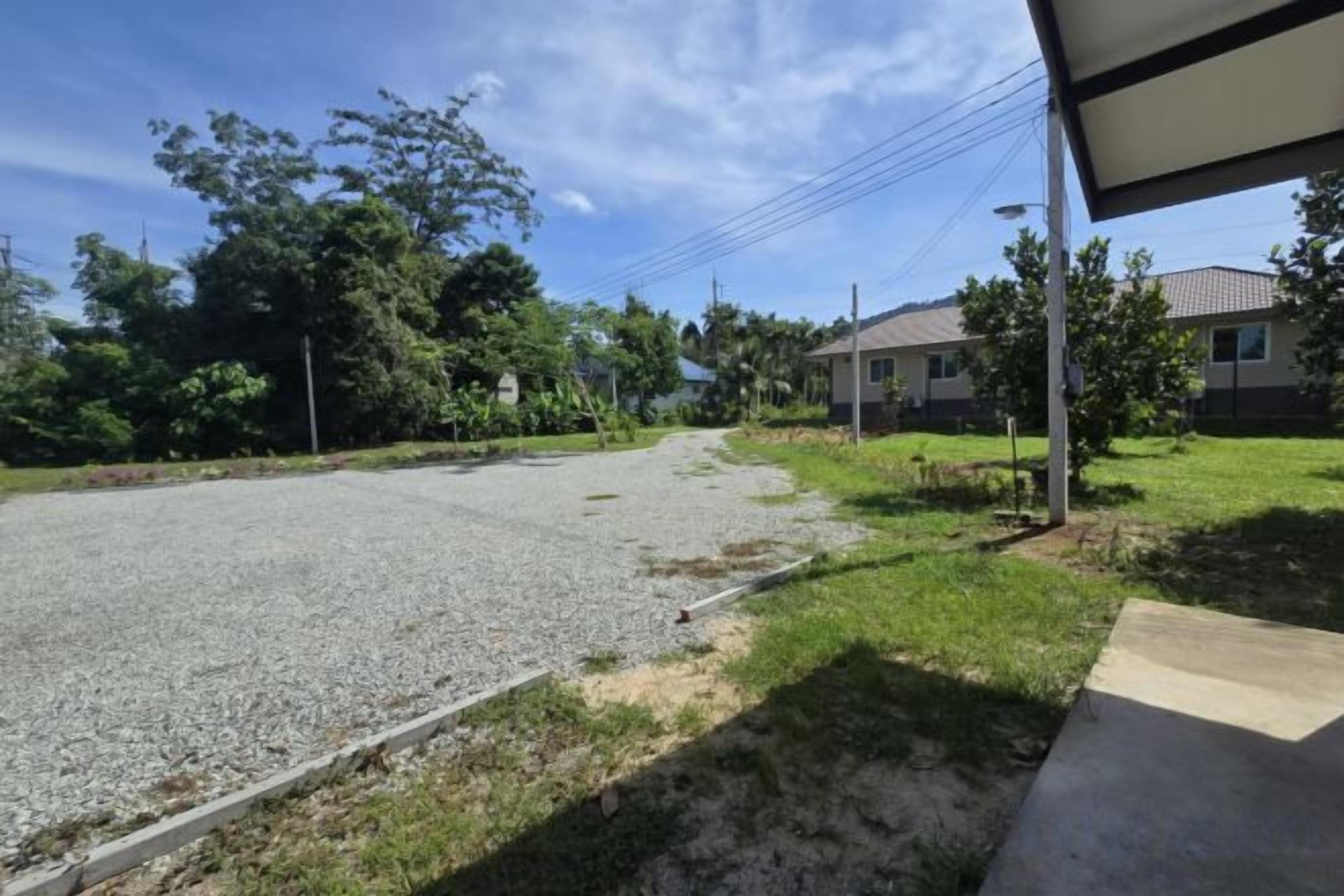 Una calle residencial con casas, un camino de grava y un área con césped.