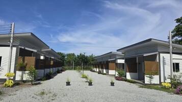 A row of modern, single-story buildings with a gravel driveway and potted plants.