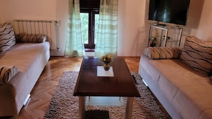 A living room with two sofas, a coffee table, a TV, and a window with curtains. - Apartments Villa Dina (Fazana)