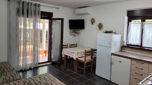 A compact kitchen with a dining table, chairs, a refrigerator, and a television. - Apartments Villa Dina (Fazana)