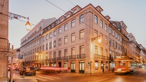 Ein mehrgeschossiges Gebäude mit klassischer Architektur, das eine markante Fassade mit Vordach und eine Reihe von Fenstern aufweist.