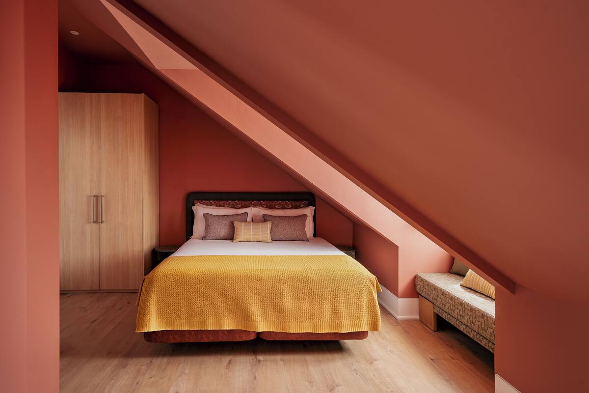 Un dormitorio con cama, armario de madera y un banco.