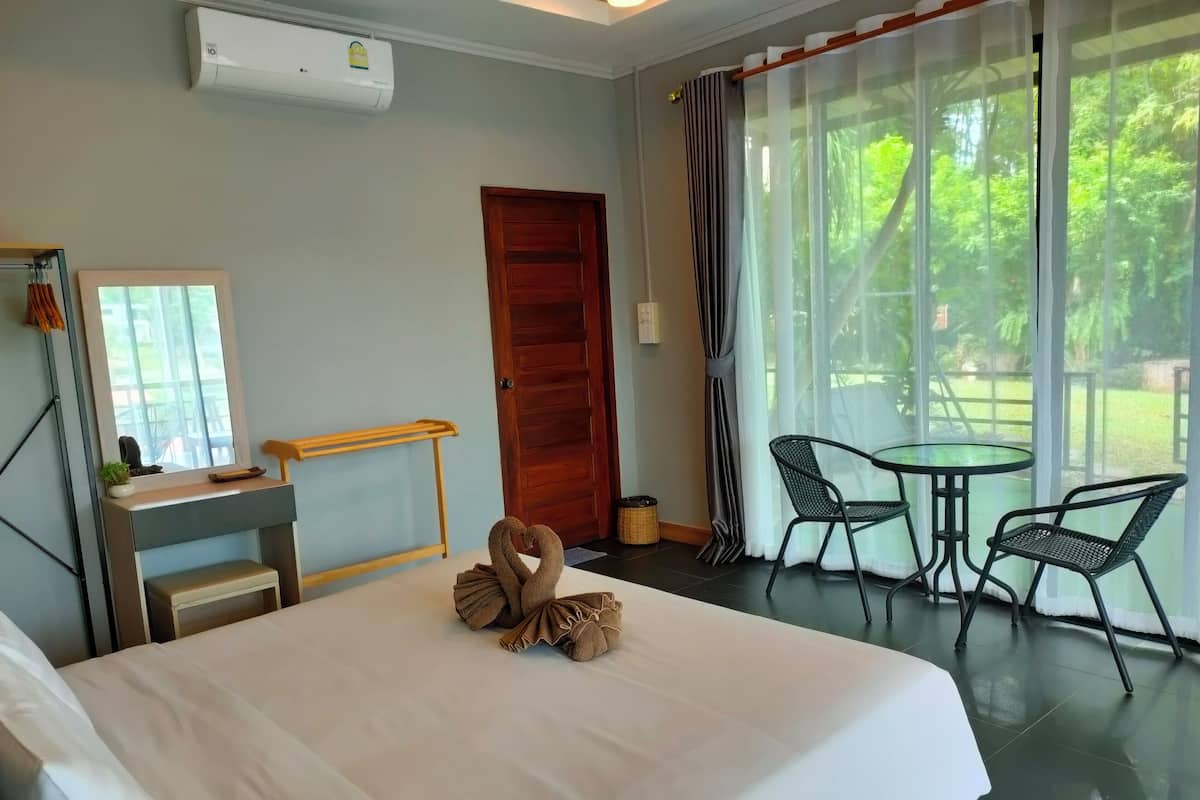 A hotel room with a bed, a desk, a chair, a small table, and a window with curtains.