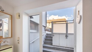 Un couloir avec un miroir, un interrupteur et une porte donnant sur un escalier.