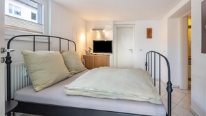 Une chambre à coucher avec un lit, une télévision, un radiateur et une fenêtre.