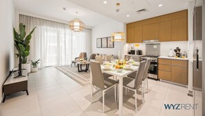 A modern kitchen with wooden cabinets, a built-in oven, and a stainless steel refrigerator. - WYZ RENT|Beachside 2BR W Pool Gym Lagoon Access (Dubai)