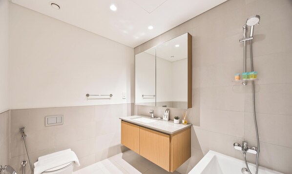 Een moderne badkamer met een vrijstaand bad, een grote spiegel en een douche met handdouche.