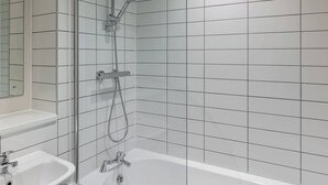 A bathroom with a bathtub, a shower, and a sink. - Modern 1BR Central Liverpool Apt with WiFi (Merseyside)