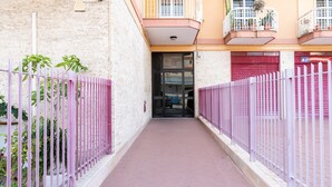 A narrow alleyway with a pink fence on both sides, leading to a building with a closed red shutter. - Roomy Family Apartment by Wonderful Italy (Bari)