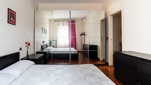 A modern bedroom with a large bed, a dresser, a mirror, and a wardrobe. - Roomy Family Apartment by Wonderful Italy (Bari)