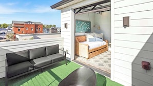 A modern outdoor patio with a sofa and a bed, a green artificial turf floor, and a view of the cityscape. - 2 Homes-Sleeps 24 | Downtown Great for Big Groups! (Nashville)
