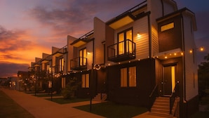 A row of modern, multi-story residential buildings with balconies and string lights, set against a sunset sky. - 2 Homes-Sleeps 24 | Downtown Great for Big Groups! (Nashville)