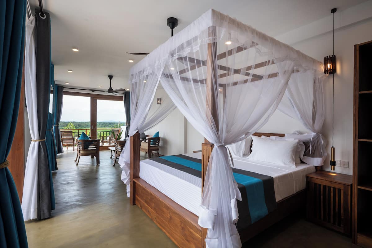 A bedroom with a four-poster bed, a wooden headboard, and a view of the outdoors.