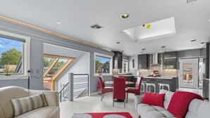 A modern living space with a dining area, kitchen, and a skylight. - Top-level duplex featuring a sleek open concept kitchen with stainless appliances, cozy fireplace, stylish furnishings, and in-unit washer/dryer. Designed for basking in the sun under skylights in thoughtful details throughout. (Vancouver)