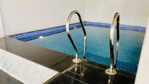 Una piscina amb rajoles blaves cristal·lines i escales metàl·liques.