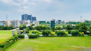 Un parc amb camins, arbres i un edifici al fons.