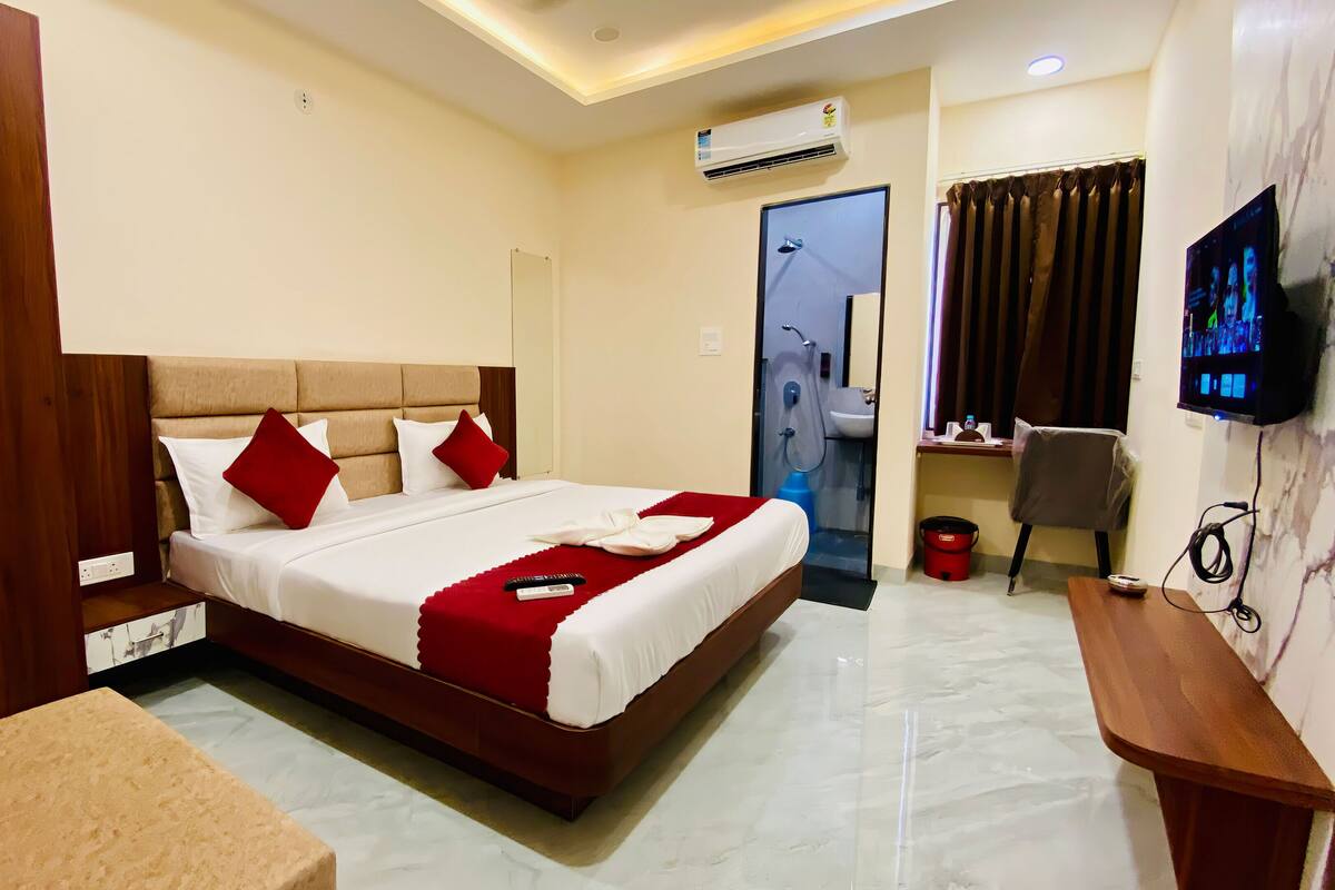 A hotel room with a bed, a desk, a TV, and a bathroom.