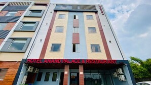Un edifici de diversos pisos amb un cartell que diu "HOTEL ANAND PALACE & RESTAURANT".