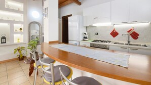 Una cocina moderna con armarios blancos, encimera de madera y una zona de bar con taburetes.