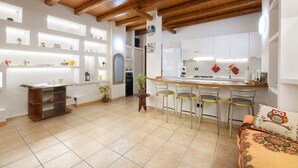 Una cocina con techo de madera, armarios blancos, una zona de comedor con sillas y una mesa pequeña.