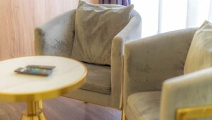 A room with a sofa, a small round table, and a window with curtains. - Flypod Hotel (Kota Kinabalu)