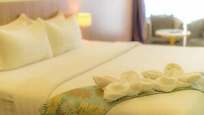 A hotel room with a bed, pillows, a bedside lamp, a chair, and a small round table. - Flypod Hotel (Kota Kinabalu)