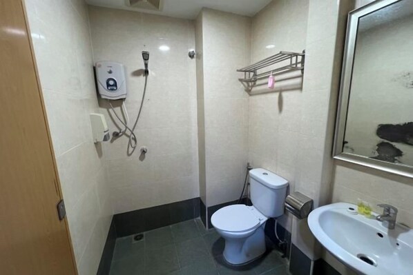 A bathroom with a toilet, a sink, a shower, and a hand dryer. - Hotel Crystal Villa (Kajang)