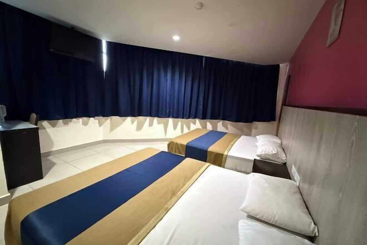 Una camera d'albergo con due letti, una scrivania, una televisione e una tenda.