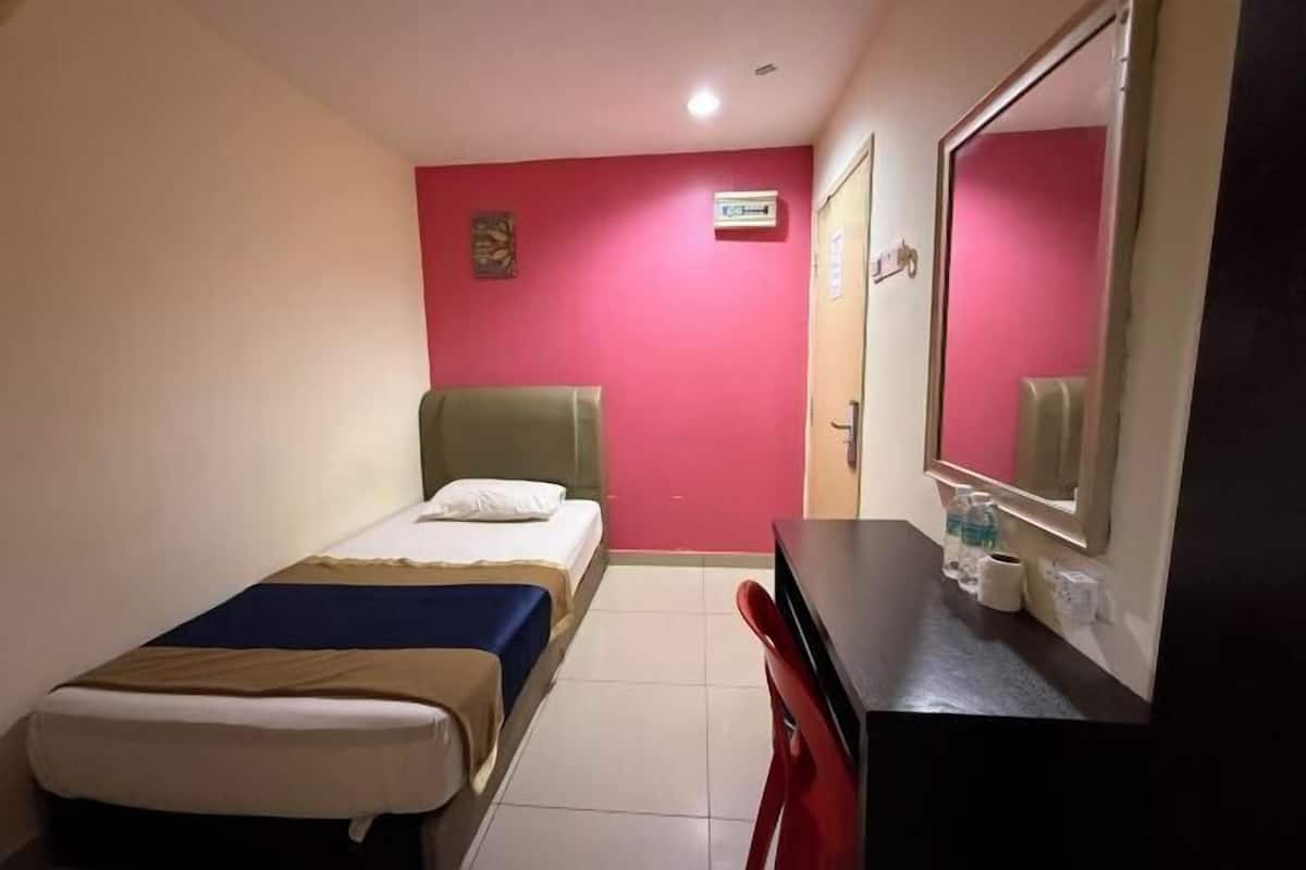Una camera d'albergo con due letti, una scrivania, uno specchio e una parete rossa.