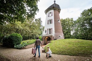 Une tour en briques dotée d’un balcon, entourée de verdure.