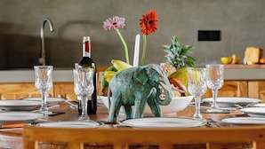 A dining table set with wine glasses, a bottle, and a decorative elephant figurine. - Villa Monkey House (Tangalle)