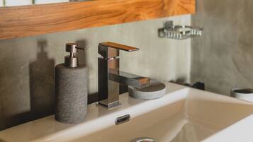 A bathroom sink with a modern faucet, a soap dispenser, and a mirror above.