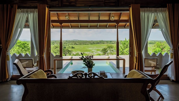 A room with a view of a green landscape, a table with chairs, and a wooden ceiling. - Villa Monkey House (Tangalle)