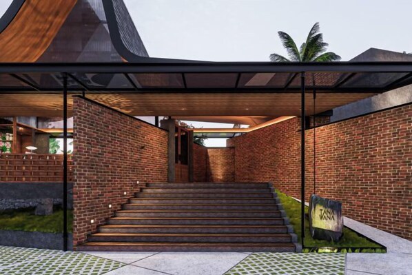 A modern building with a brick facade, a staircase leading to an entrance, and a covered area with a roof.
