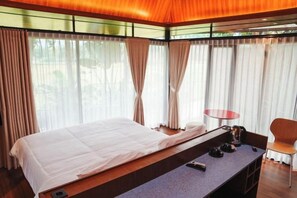 Una habitación de hotel moderna con una cama grande, una mesita pequeña y una silla.