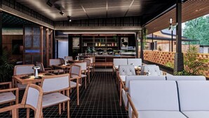 A modern restaurant with wooden furniture and a brick wall. - Tanawana Living Borobudur (Borobudur)