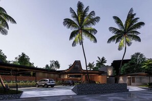 A modern house with a car parked in the driveway, surrounded by palm trees.