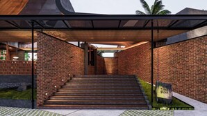 A modern building with a brick exterior, a staircase leading to an entrance, and a covered area with a wooden ceiling. - Tanawana Living Borobudur (Borobudur)