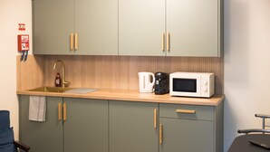Una kitchenette con microondas, cafetera y pileta. Hay un extintor en la pared y una toalla colgada del mueble.