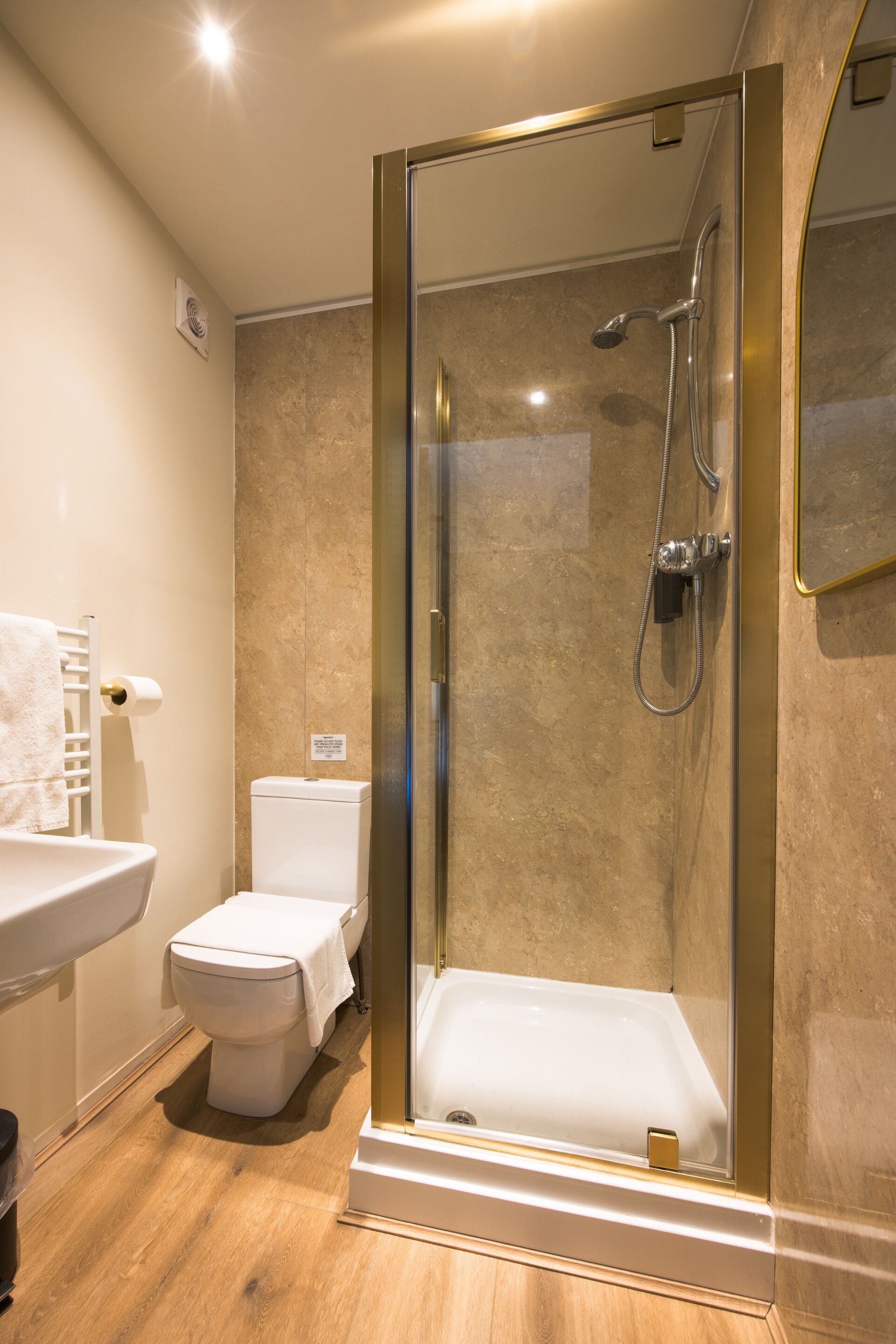 Un baño moderno con ducha acristalada, inodoro y lavamanos.