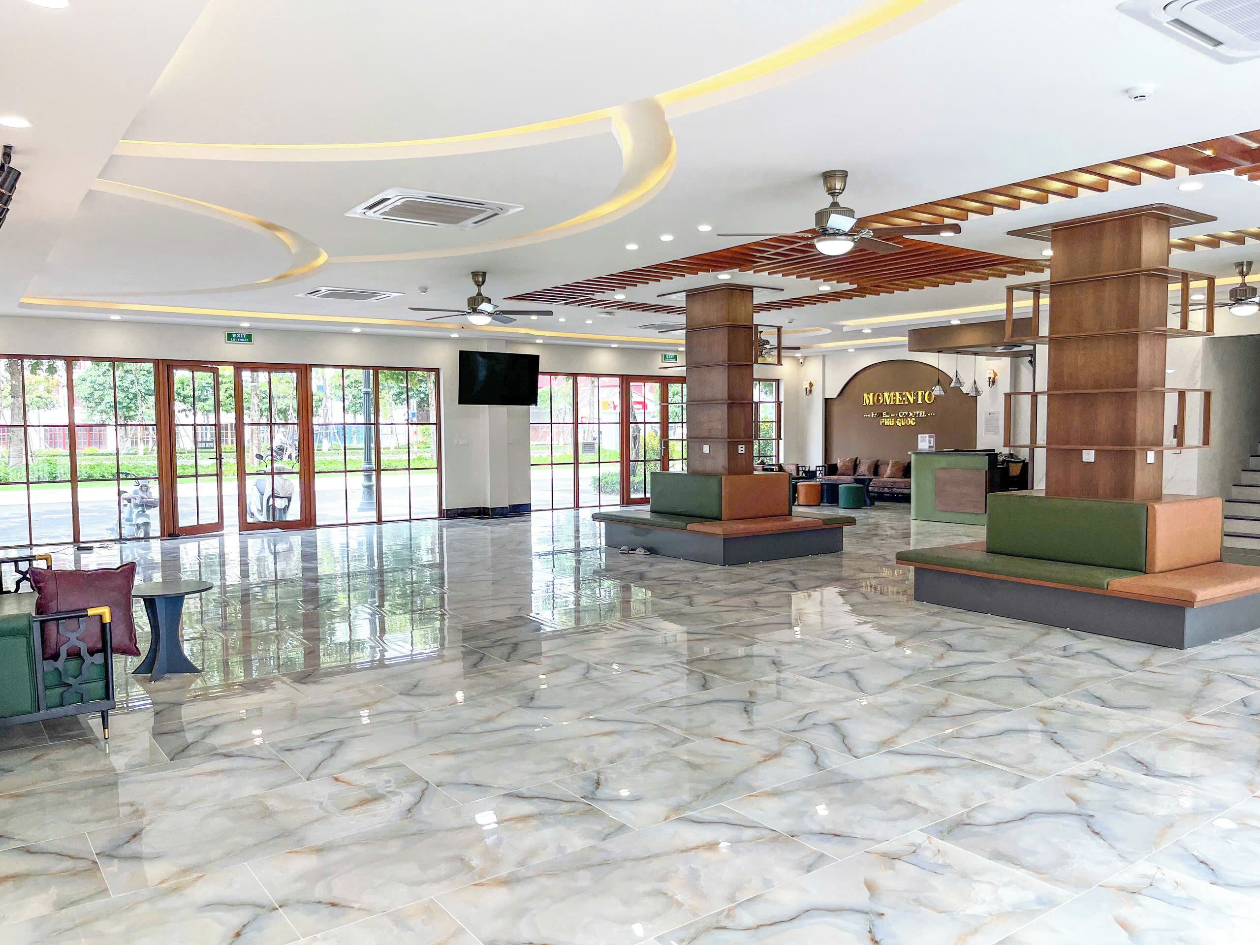 A spacious lobby with marble flooring, wooden accents, and large windows offering views of the outdoors.