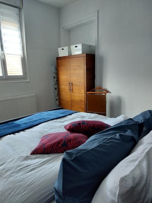 A bedroom with a bed, a wardrobe, and a window.