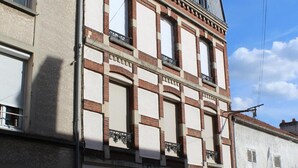 Un edificio a più piani con uno stile architettonico classico, caratterizzato da un balcone ben visibile al secondo piano e un portone per garage al piano terra.