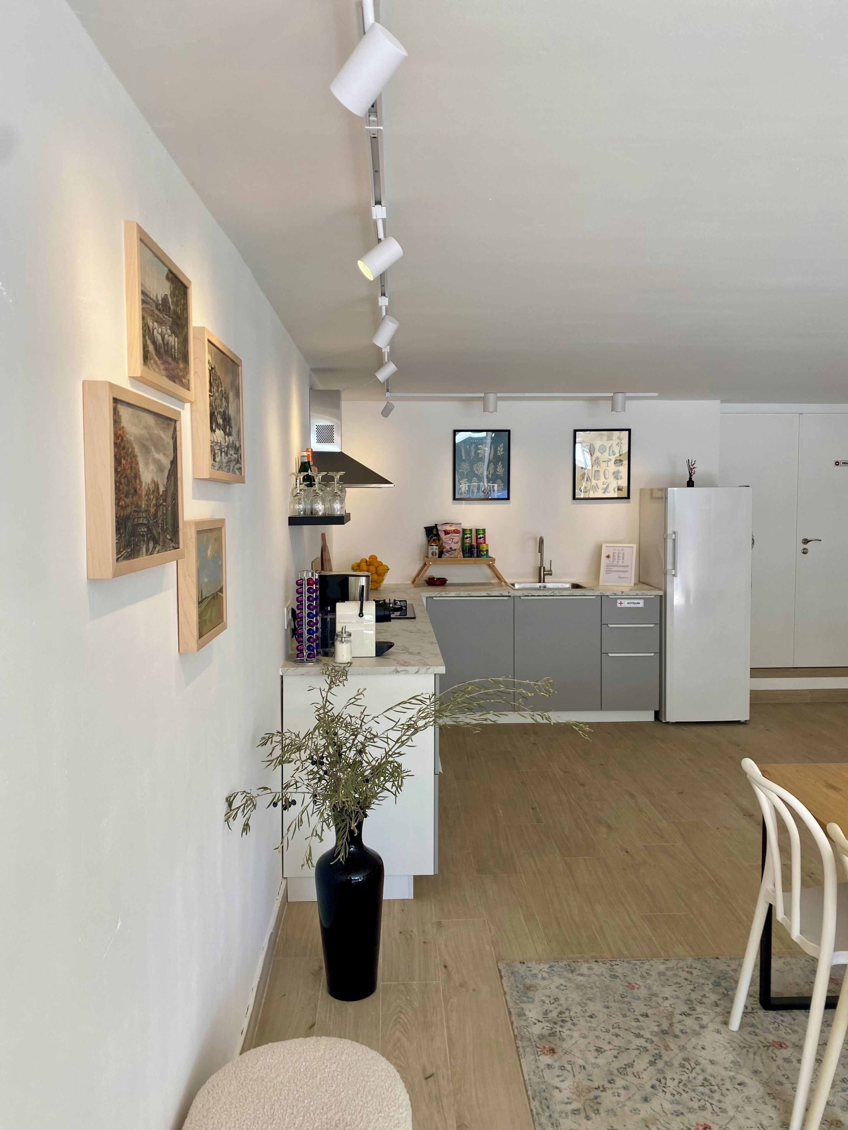 Una cocina moderna con una isla central, una zona de comedor con una silla y obras de arte en las paredes.