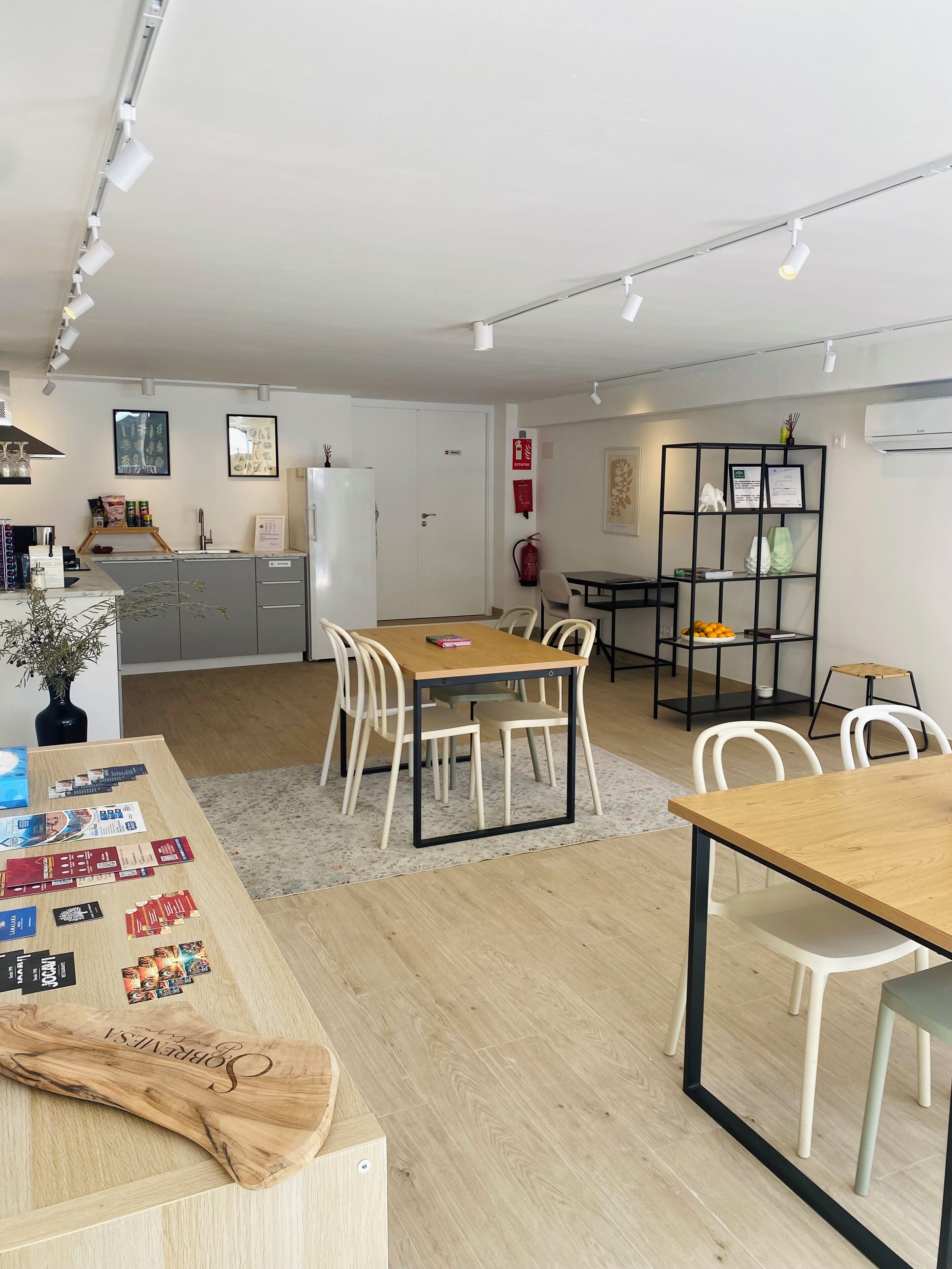 Une cuisine moderne avec des meubles blancs, une table à manger en bois et une bibliothèque noire.