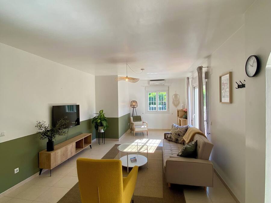 Un salón amplio con sofá, sillón amarillo y una mesa de centro.
