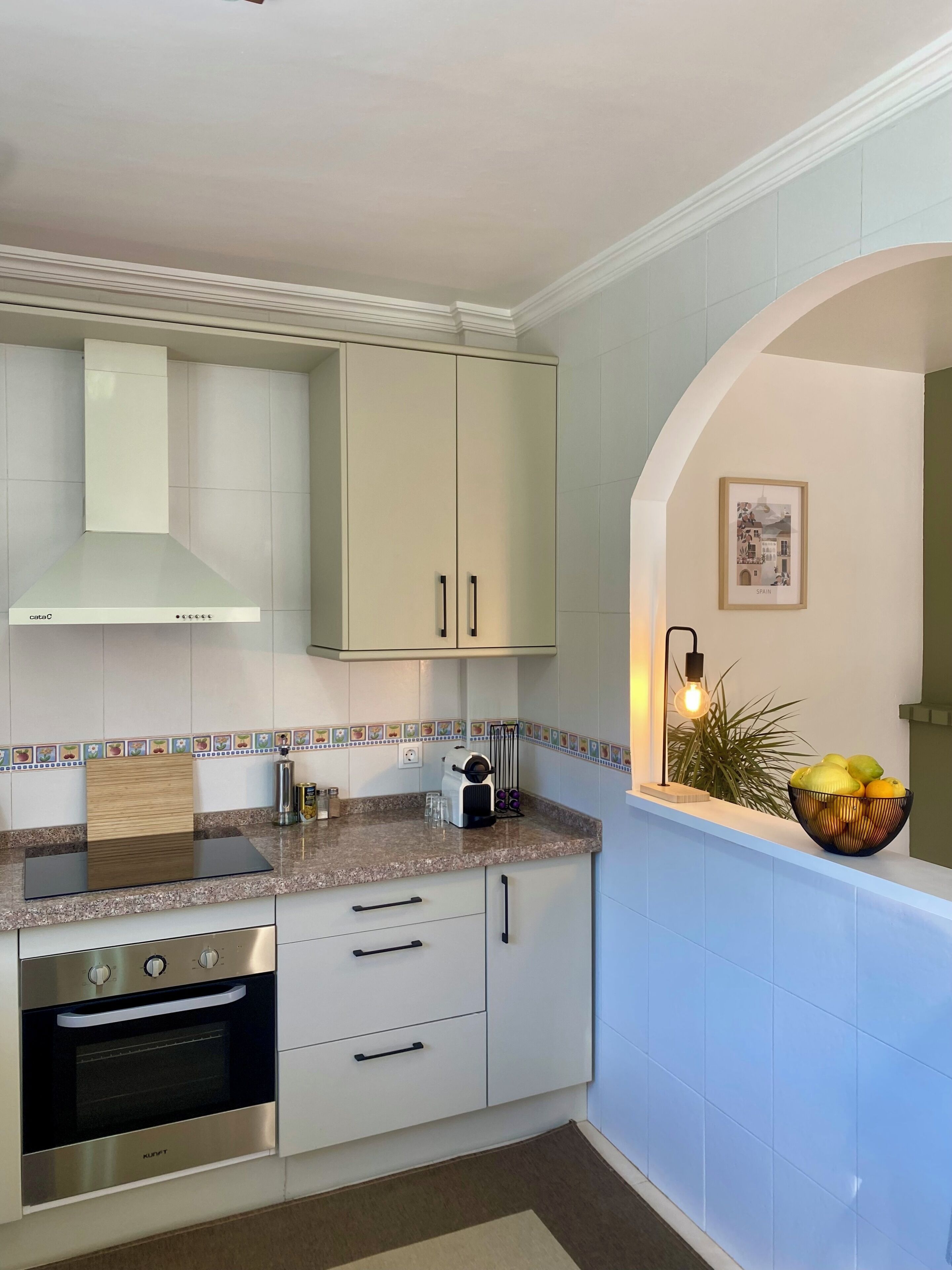A modern kitchen with white cabinets, a built-in oven, a stainless steel range, and a tiled backsplash.