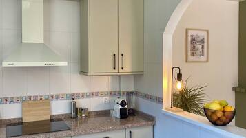 A modern kitchen with white cabinets, a built-in oven, a stainless steel range, and a tiled backsplash.