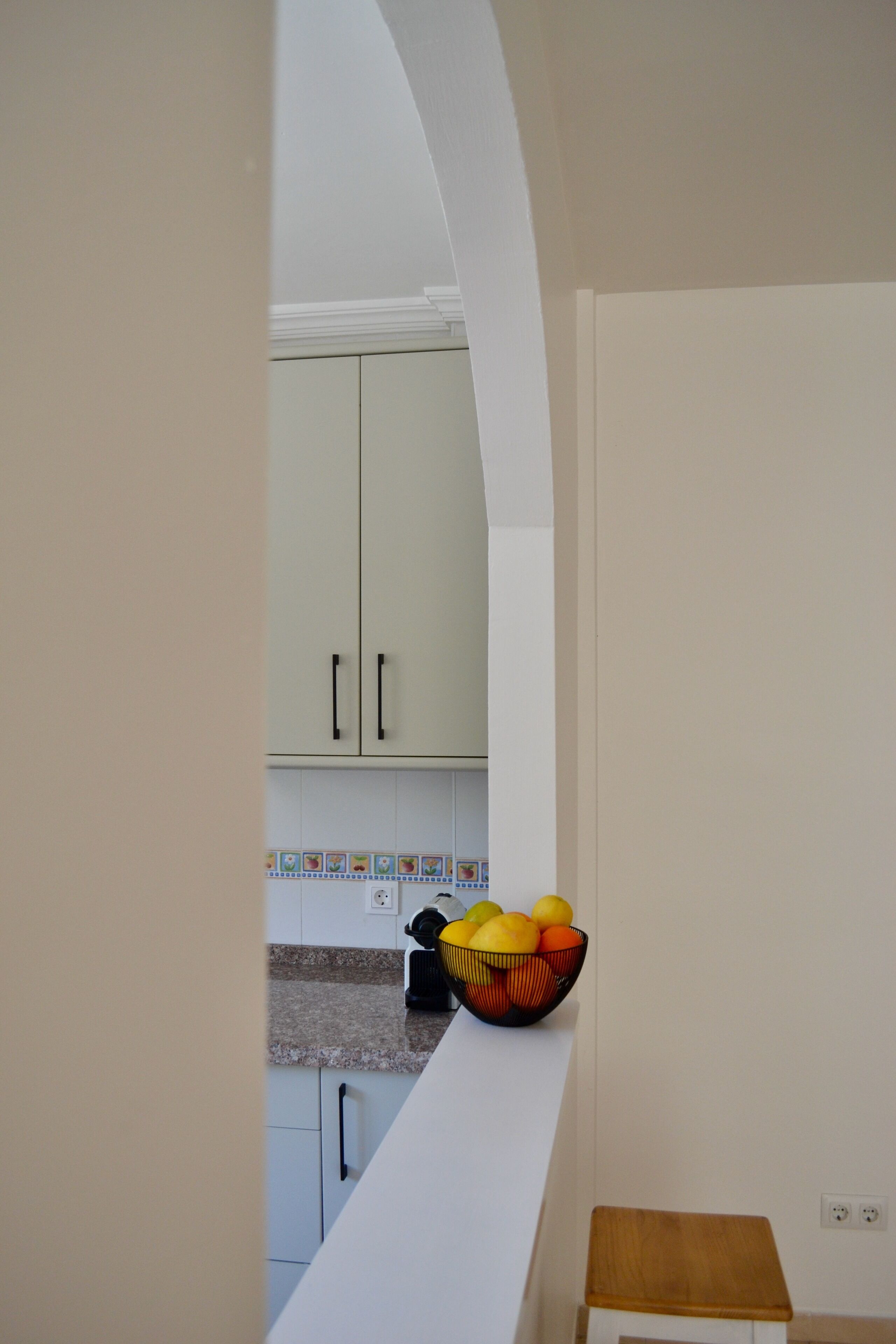 A kitchen with white cabinets, a countertop, and a fruit bowl.