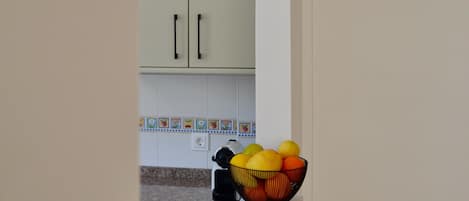 A kitchen with white cabinets, a countertop, and a fruit bowl.